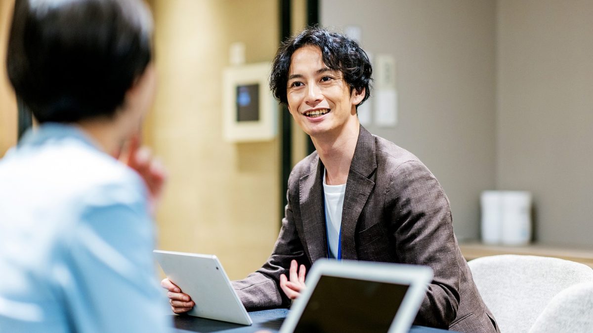 タブレットを片手に持ち商談相手を説得する男性
