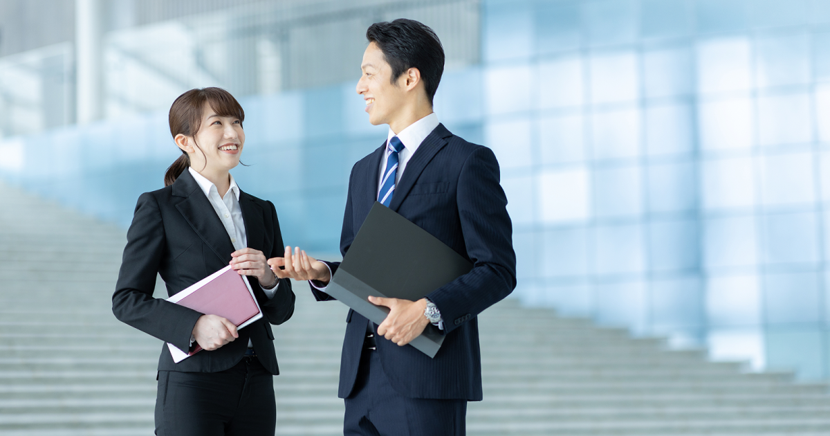 階段の前で話し合うスーツ姿の男女