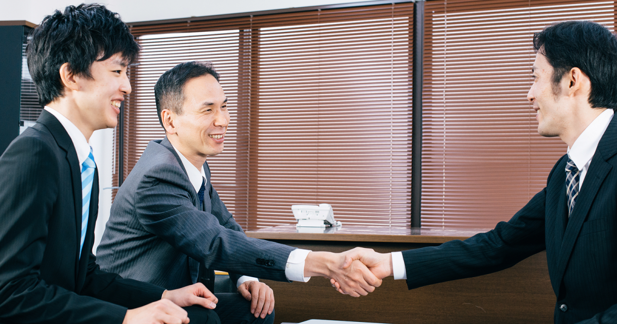 オフィスで握手をするスーツ姿の男性