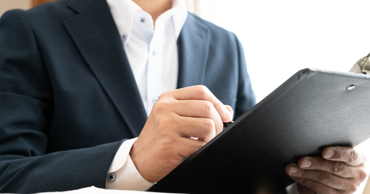 バインダーに挟んだ紙にメモを書く様子