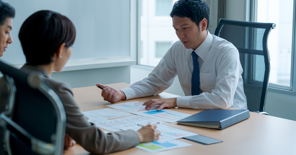 会議室で資料を見比べながら真剣に話し合う様子