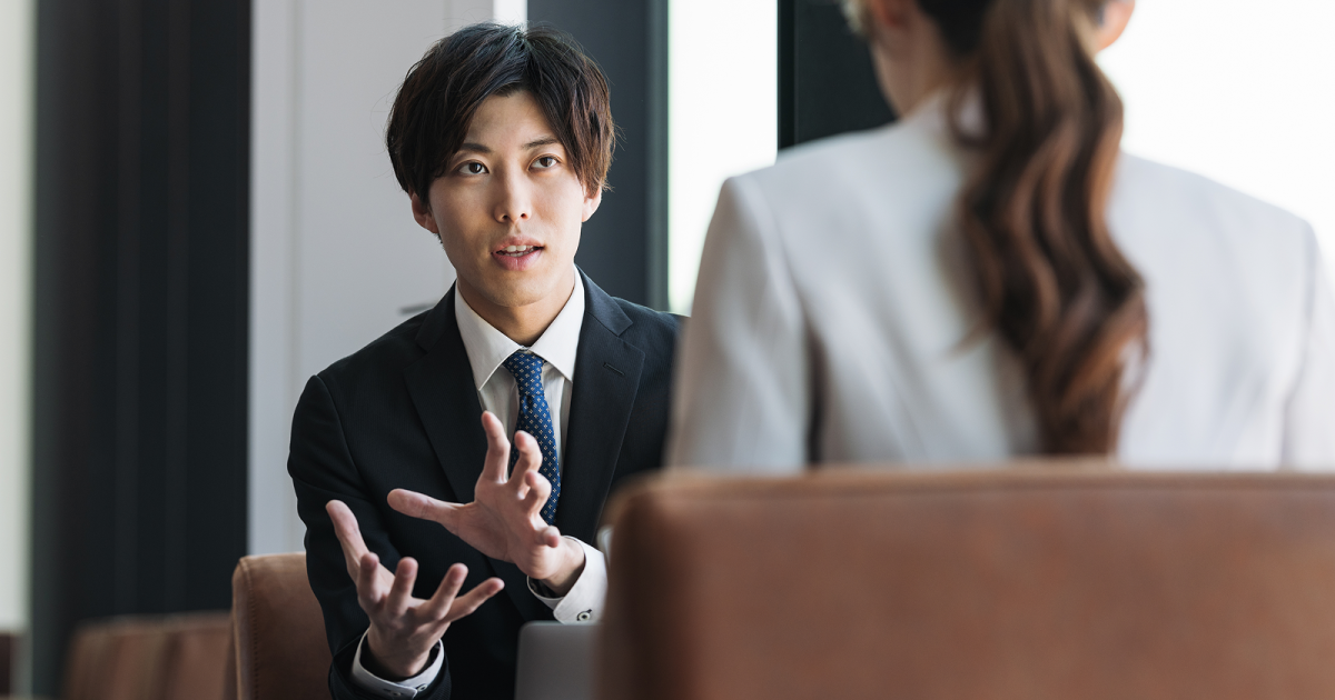 ジェスチャーをしながら話すスーツ姿の男性