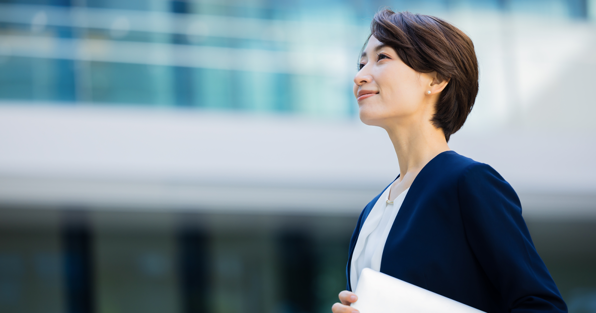 ノートパソコンを脇に抱えて歩く女性