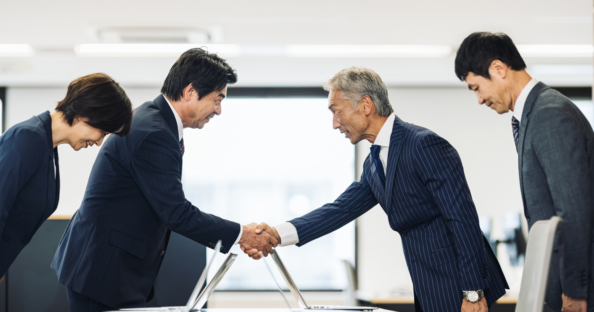 オフィスで握手を交わす年配の男性