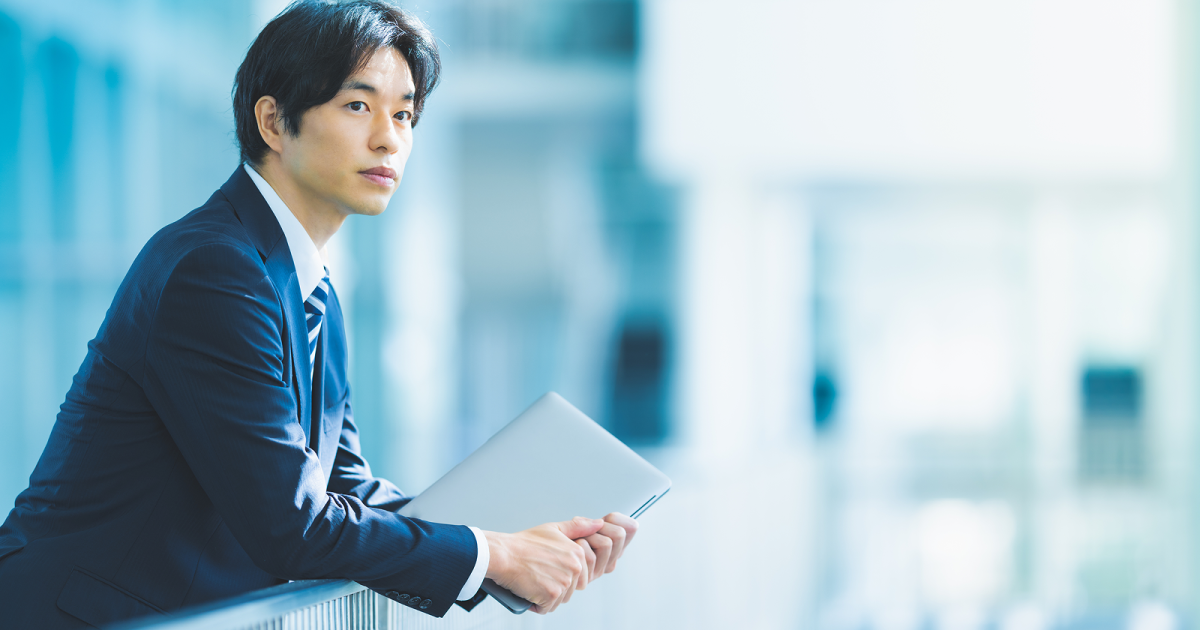 柵に寄りかかるスーツ姿の男性