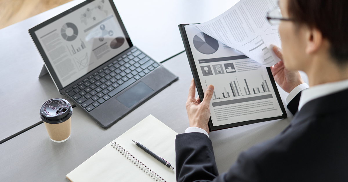 タブレットに移した資料と紙の資料を比較する男性
