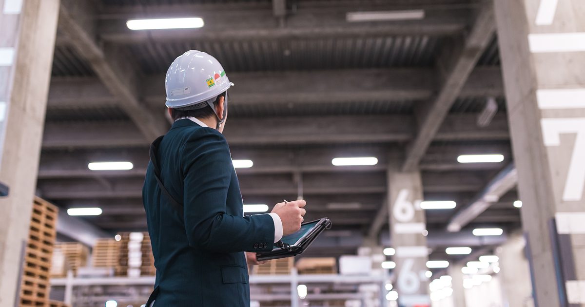 倉庫でヘルメットを着けて働くスーツ姿の男性