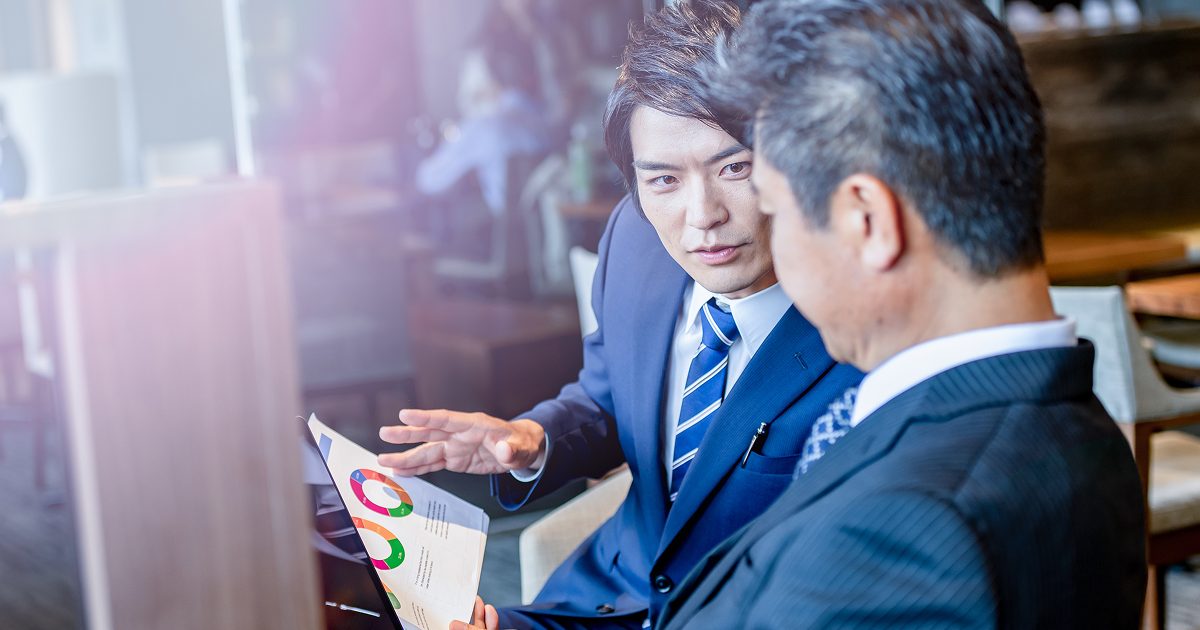 印刷された資料を読みながら話し合うビジネスマン