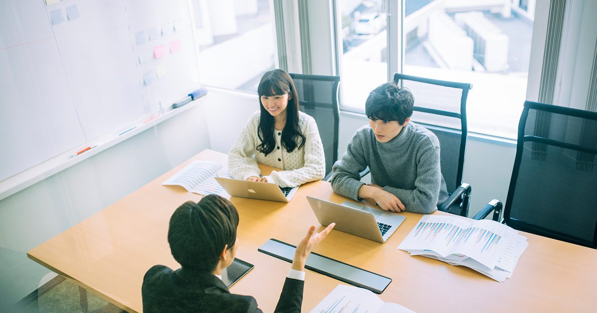 会議室で話し合う若い男女