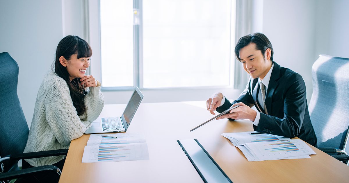 会議室でタブレットを見る男女
