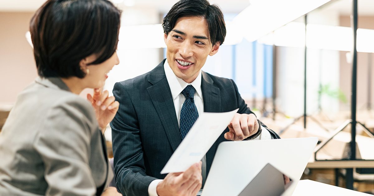 紙の資料を見ながら話し合う男女