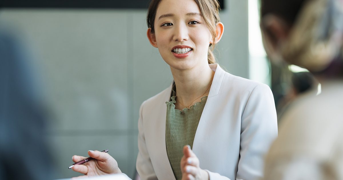 ボールペンを片手に持ち話す女性