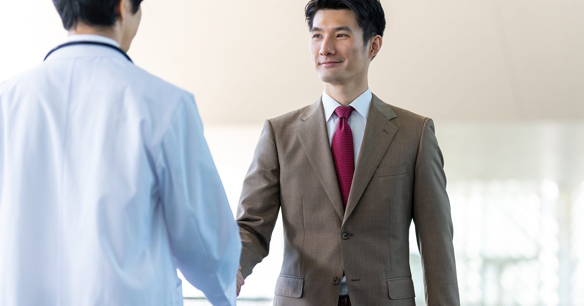 握手をするブラウンのスーツを着た男性