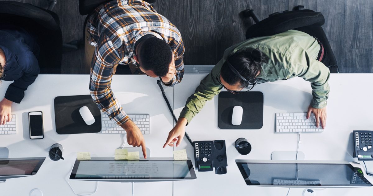 パソコンを指さす男性2人