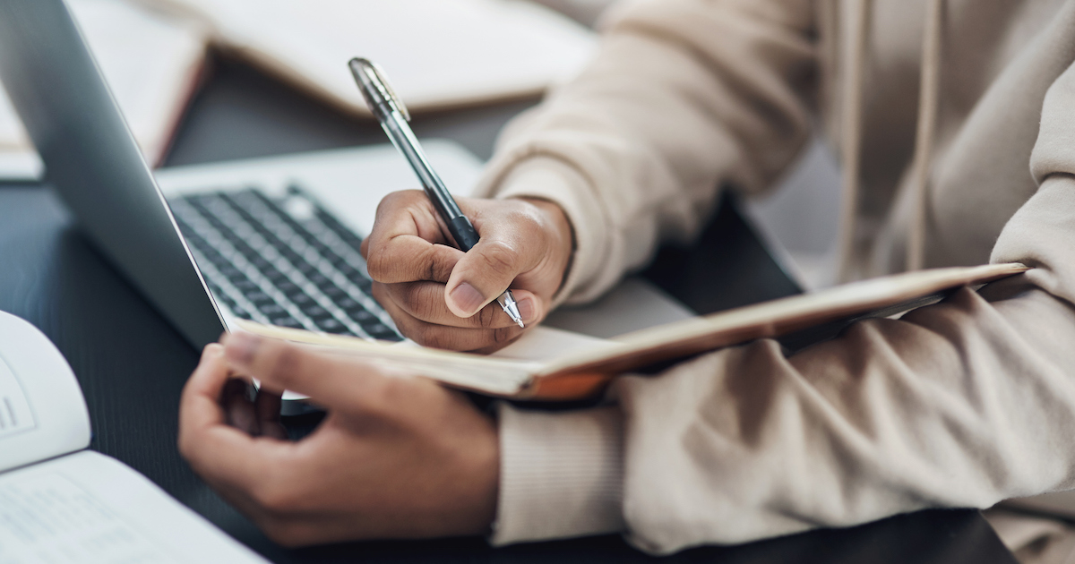 ノートパソコンを見ながらメモを取る様子