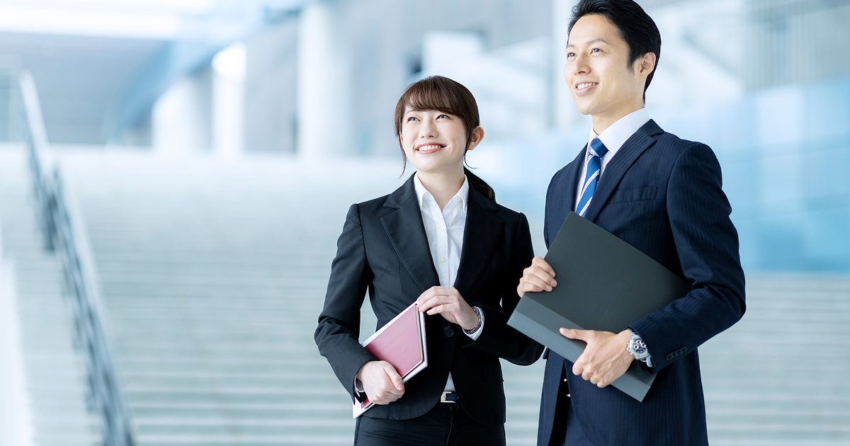 階段の前に立つスーツ姿の若い男女