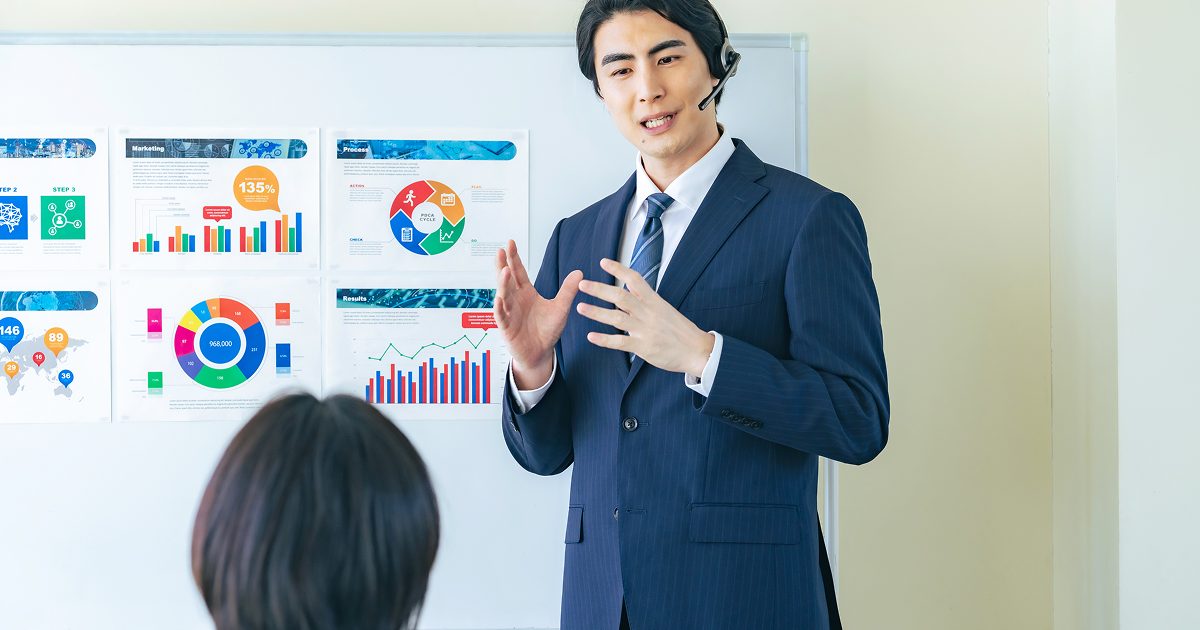 ホワイトボードに資料を貼って説明する男性