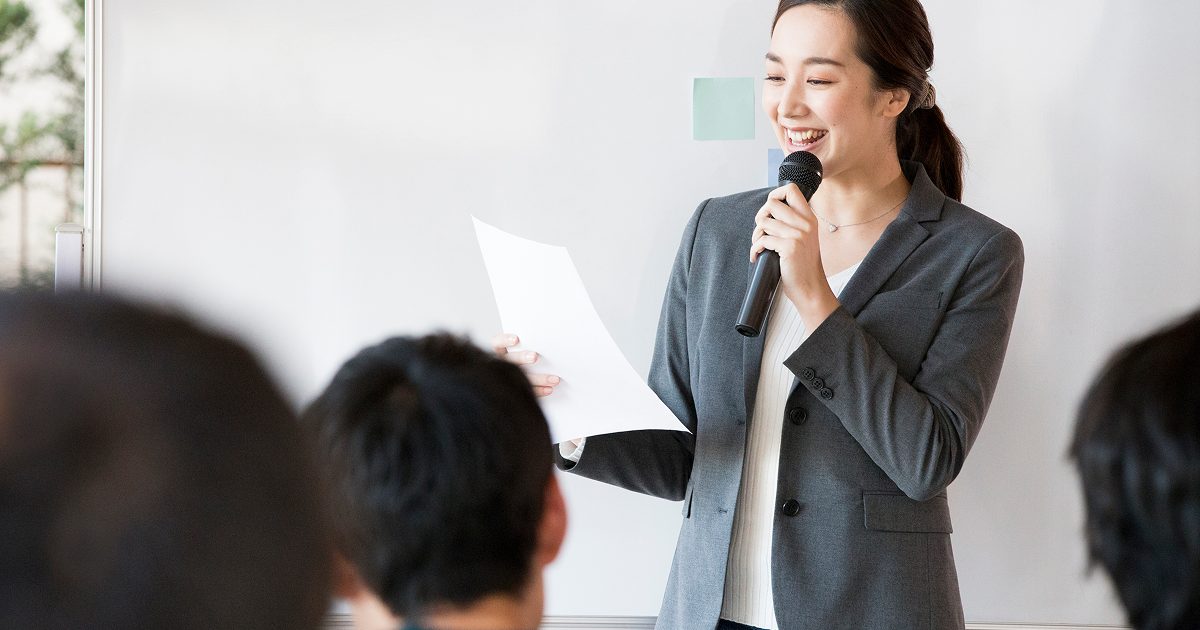 マイクを持って笑顔で話す女性