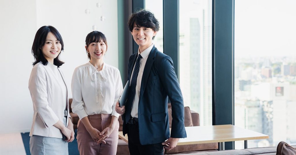 オフィスに並んで立つ3人の男女