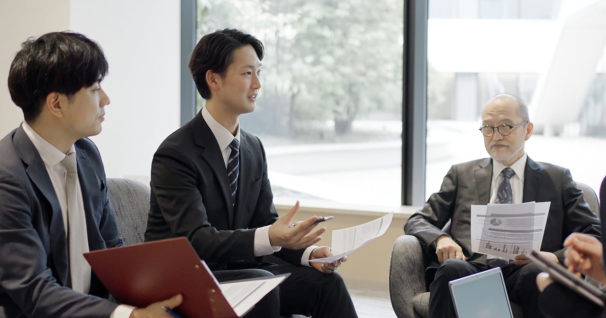 経営層に向けてプレゼンをする若い男性