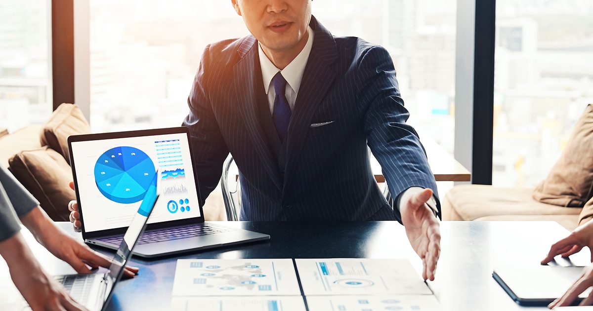 紙の資料を見せながら説明をするスーツ姿の男性