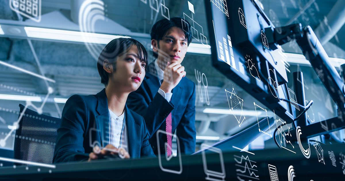 真剣な表情でモニターを見るスーツ姿の男女