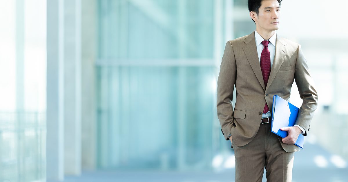 ファイルを小脇に抱ええて立つスーツ姿の男性