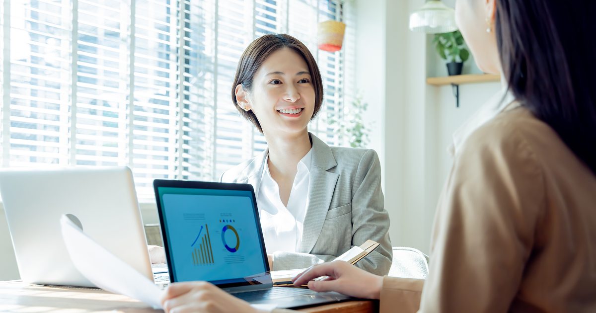 オフィスでノートパソコンを操作しながら話し合う女性