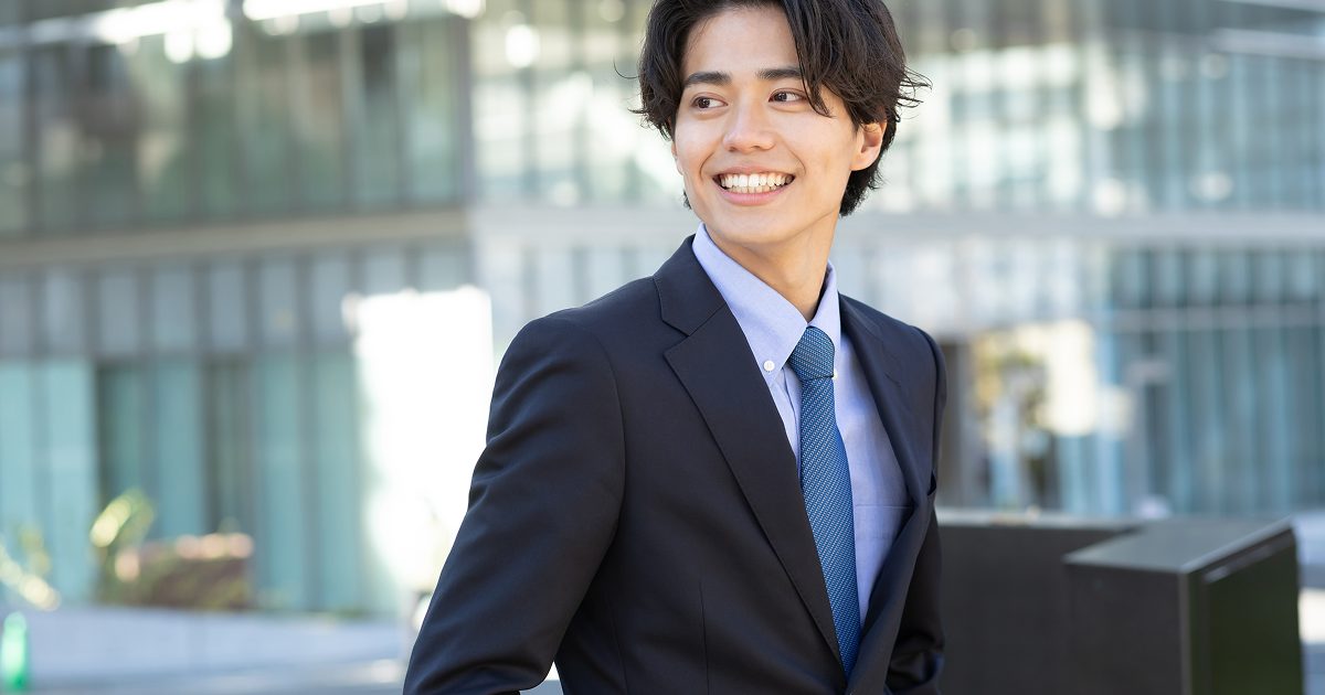オフィス街を笑顔で歩くスーツ姿の男性