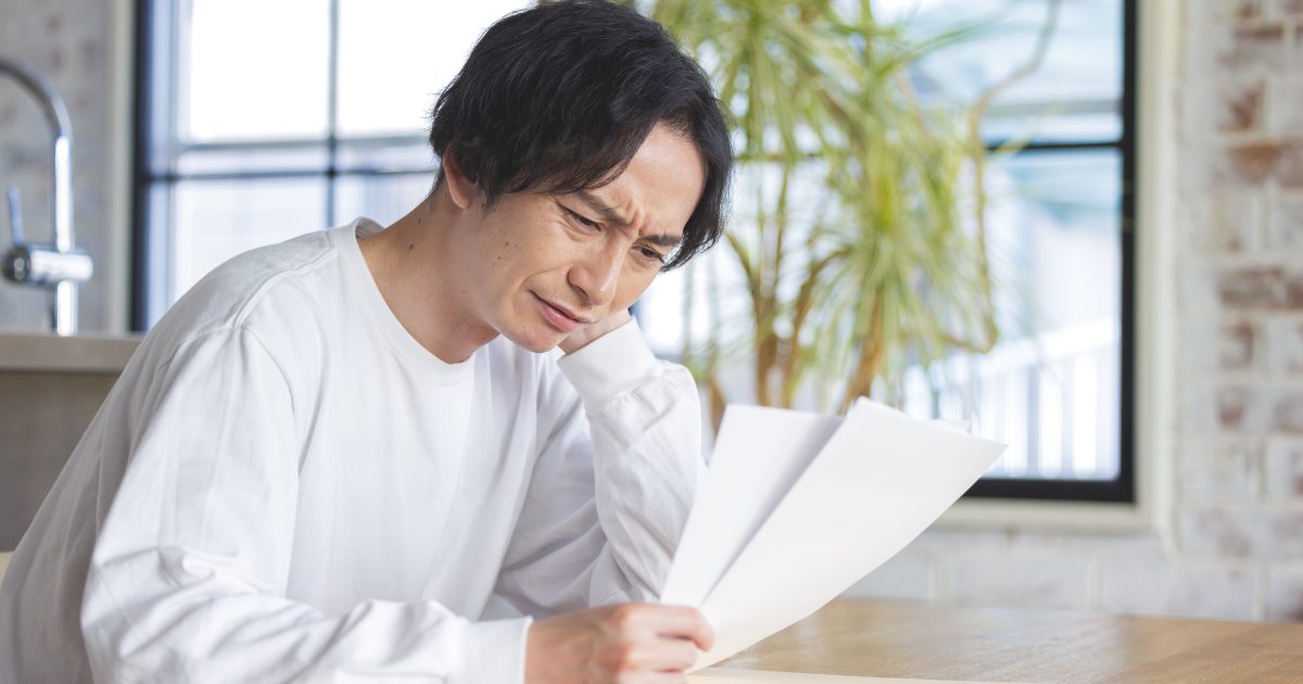 資料を見ながら頭を抱える男性