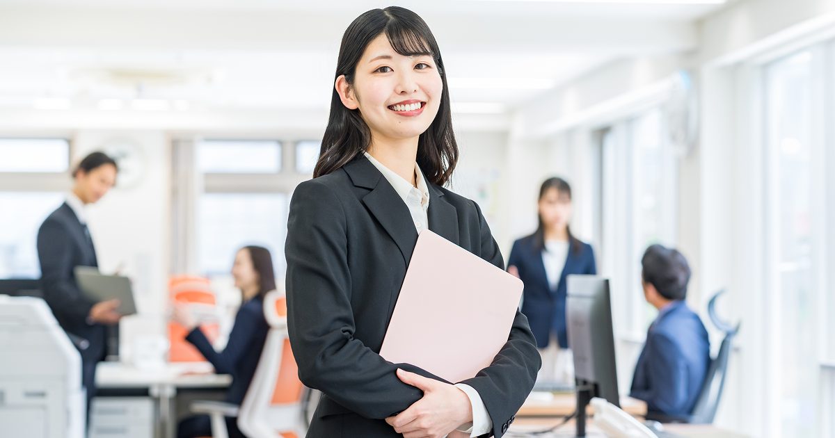 ノートパソコンを持つスーツを着た女性